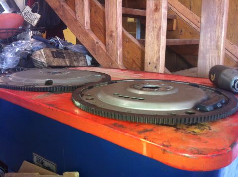 1982 Ford Bronco - Two flywheel parts are visible on a workbench with wooden stairs behind them.