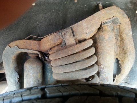 1995 Ford Bronco - Close-up view of heavily rusted suspension components and a tire.