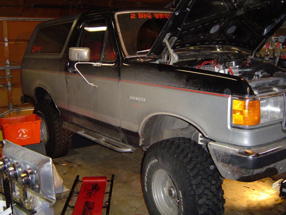Lifted two-tone Bronco in garage with hood up, 2 BIG decal on rear glass