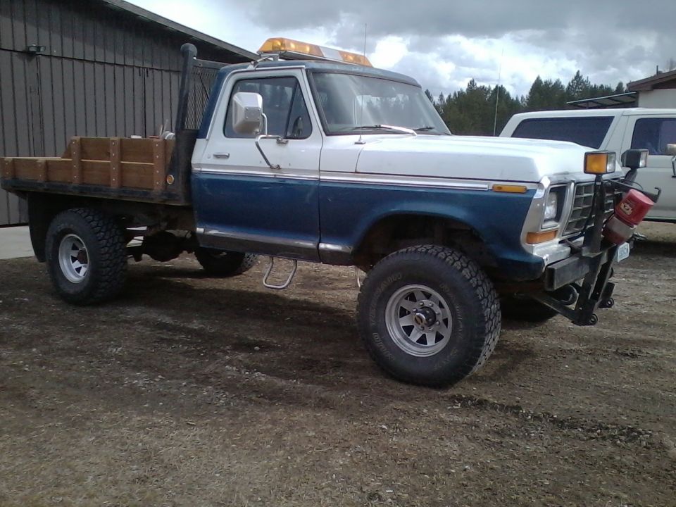 1973 Ford F-250 flatbed truck, blue and white, with wooden bed and yellow light bar