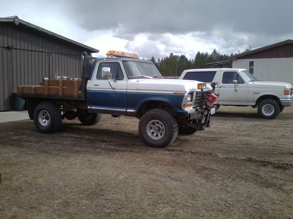 1973 Ford F-250 flatbed truck, blue and white, with amber lights on roof