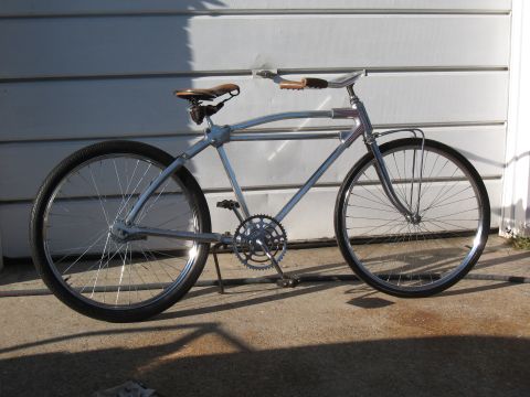 Silver cruiser bicycle with leather seat and handlebars parked on concrete