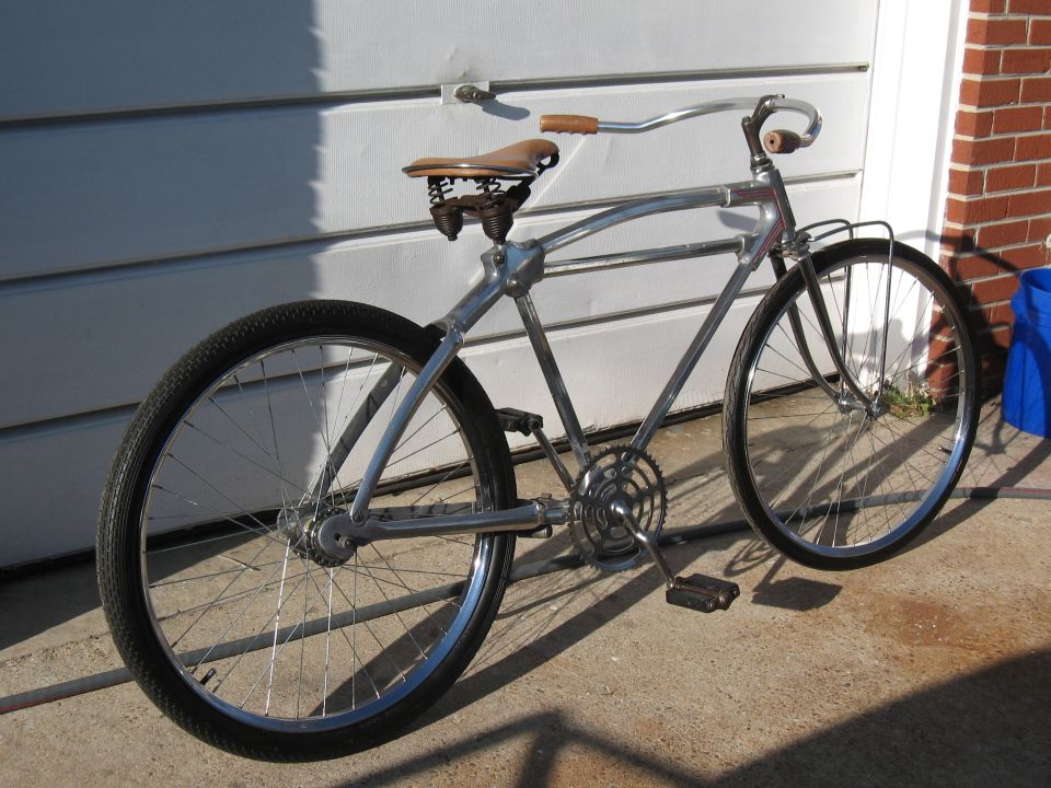 Chrome cruiser bicycle with leather saddle and handlebars, parked outside a garage