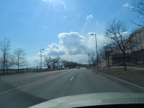 1971 Ford Ranchero - A view from a vehicle driving down a road on a sunny day with clouds.
