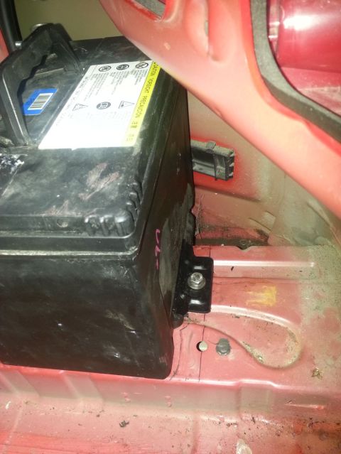 2010 Hyundai Genesis - Close-up of a car battery mounted in a vehicle's interior compartment.