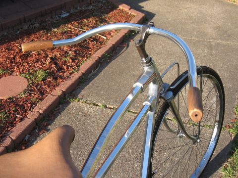 Chrome bicycle handlebars with wooden grips and front wheel