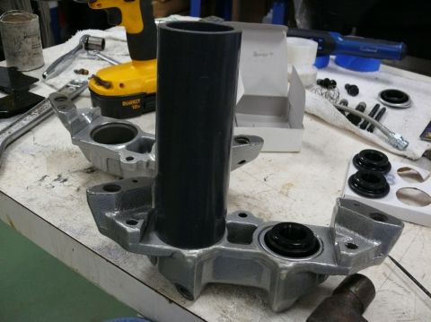 Car brake caliper parts laid out on a workbench with tools and a black tube
