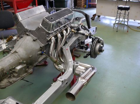 Chevrolet V8 engine with chrome headers and exhaust pipes on a bare chassis