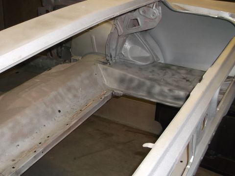 1967 Ford Mustang - The bare metal interior of a car, possibly a trunk area, is shown with primer applied.