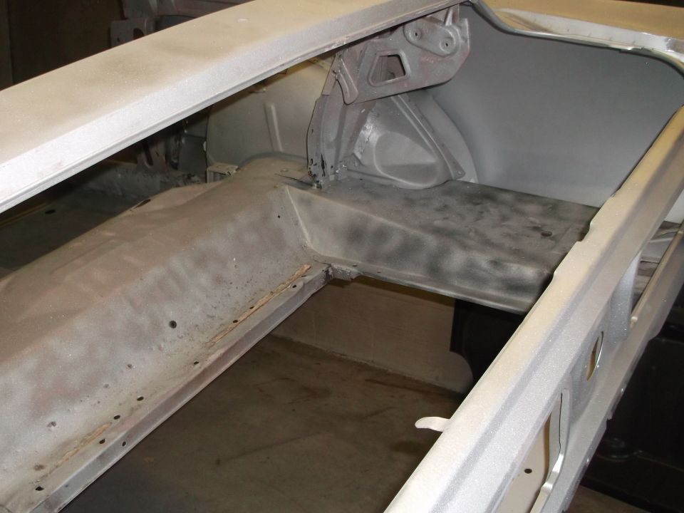 Car body interior, likely trunk area, showing metal structure and primer