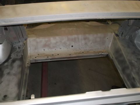 1967 Ford Mustang - The bare metal interior of a car's trunk shows signs of rust and wear.