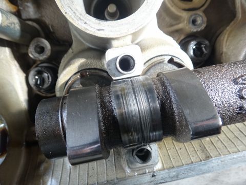 1993 Ford Taurus - Close-up view of a damaged camshaft, showing significant wear and scoring on its surface.