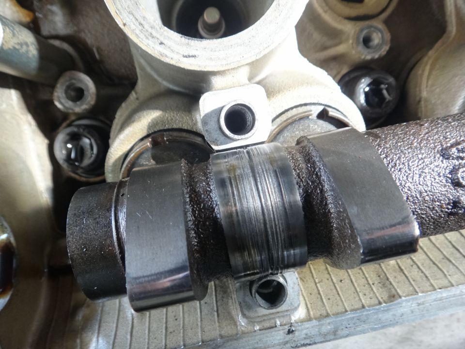 Worn camshaft with visible scoring and oil residue