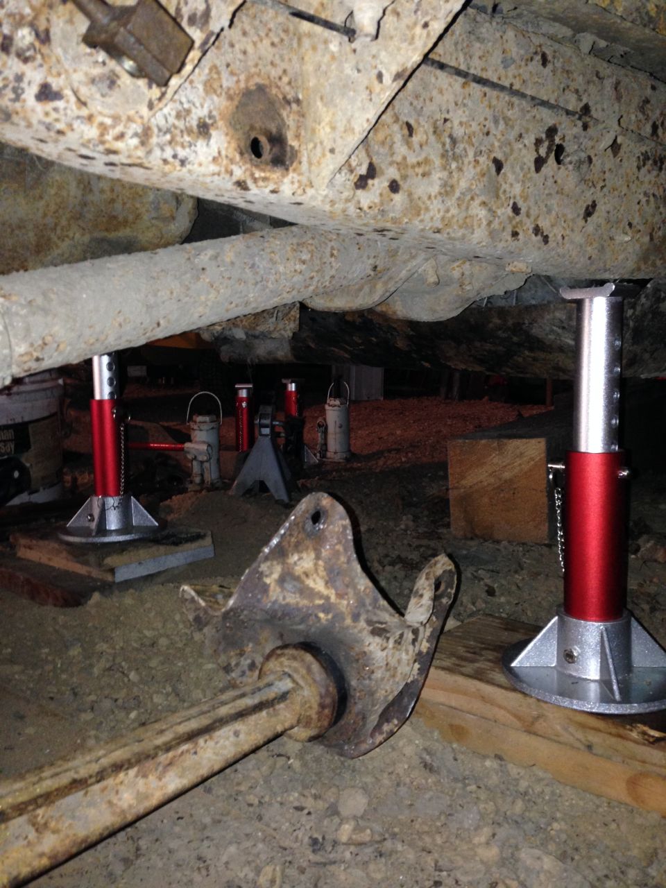 Vehicle frame and suspension components supported by red and gray jack stands