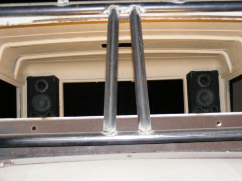 Interior view of a vehicle with two speakers mounted behind metal bars