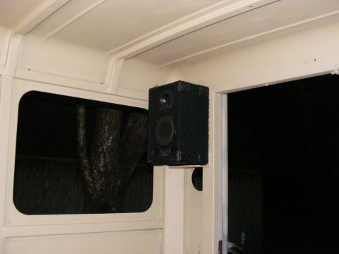 Interior view of a vehicle showing a black speaker mounted on a pillar next to a window