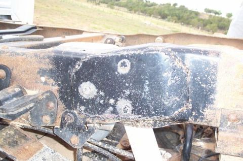 1990 Ford Bronco - The underside of a vehicle shows heavily rusted frame components and suspension parts, with a white paper partially visible.