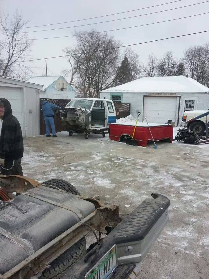 Truck chassis with fuel tank, red truck bed, and white cab with blue stripe on wheels