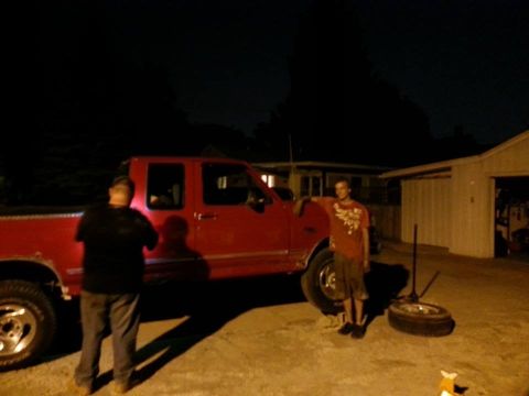 1995 Ford F-150 - Two men stand next to a red 1995 Ford F-150 pickup truck at night, with a spare tire on the ground.