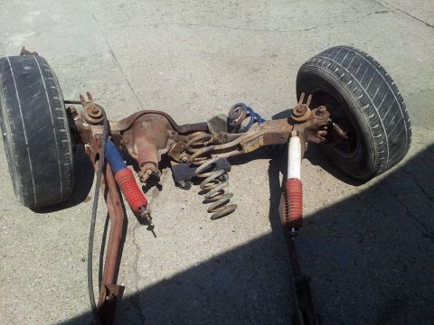 1995 Ford F-150 - A disassembled rear axle assembly sits on the ground, showing its components.