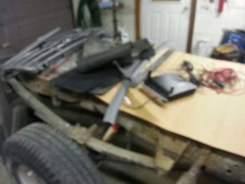 1995 Ford F-150 - Disassembled truck chassis and parts are laid out on a workbench in a garage.