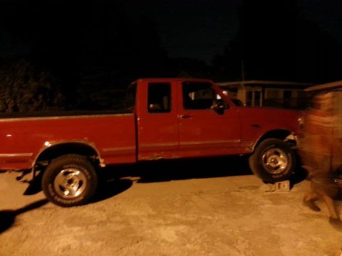 1995 Ford F-150 - This red 1995 Ford F-150 pickup truck is shown from the side at night.