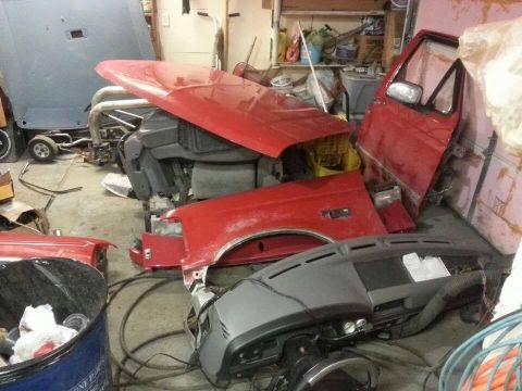 1995 Ford F-150 - Various red truck body panels and a dashboard are stored in a cluttered garage setting.