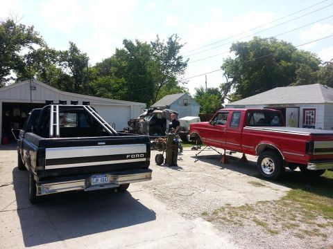 1995 Ford F-150 - Two Ford trucks are parked in a driveway, one is on jack stands with a welding setup nearby.
