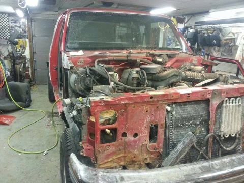 1995 Ford F-150 - The front of a red truck is dismantled, revealing the engine and radiator components.