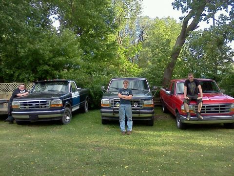 1995 Ford F-150 - Three Ford F-150 pickup trucks are parked in a yard with people posing near them.