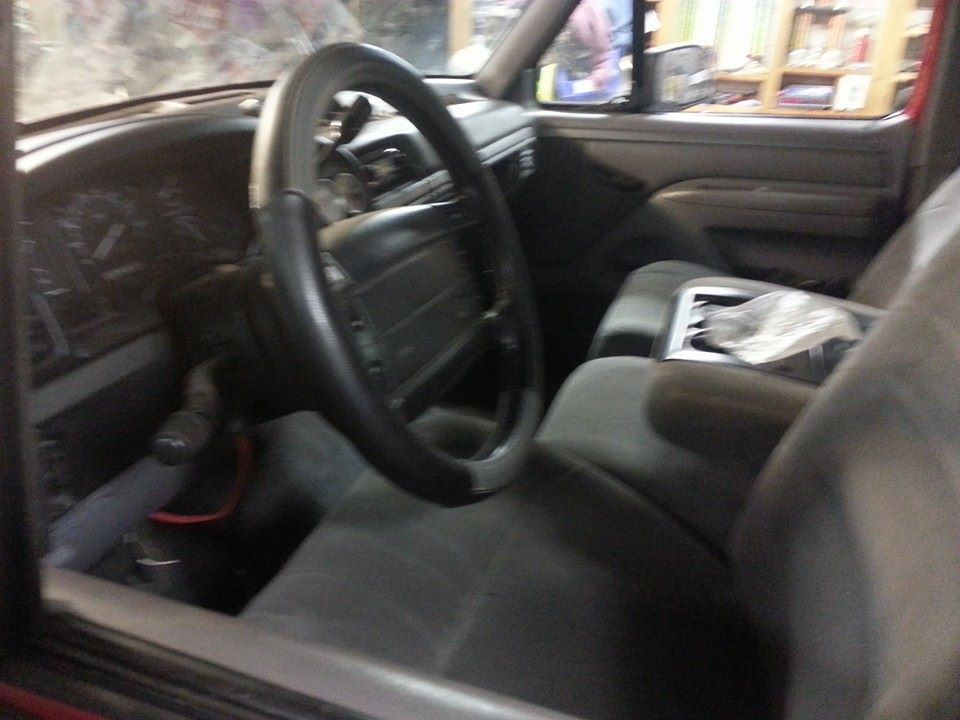 Interior shot of a truck's dashboard and seats, showing the steering wheel, center console, and part of the passenger seat