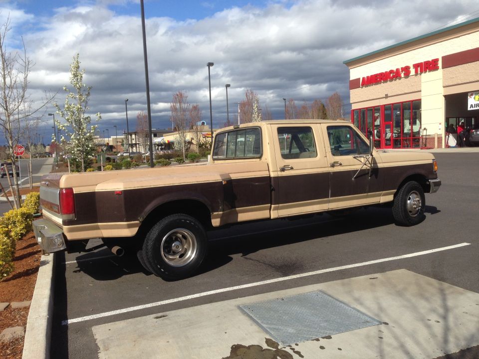 Two-tone brown and tan Ford F-350 Crew Cab Dually pickup truck parked in front of America's Tire
