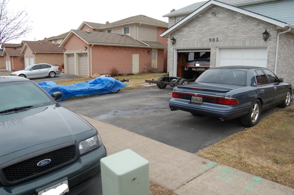 Blue Ford SUV and dark Mercury Grand Marquis sedan parked in a suburban driveway