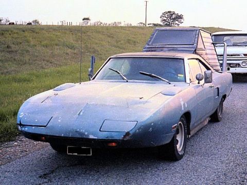 1972 Ford Ranchero - A blue 1970 Plymouth Superbird is parked on a gravel road, towing a camper shell.
