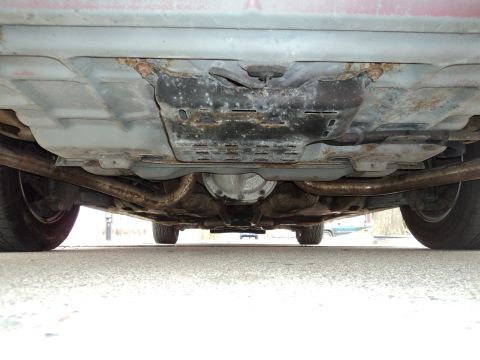 2004 Mercury Grand Marquis - The underside of a red 2004 Mercury Grand Marquis reveals rusted exhaust components and a rear differential.