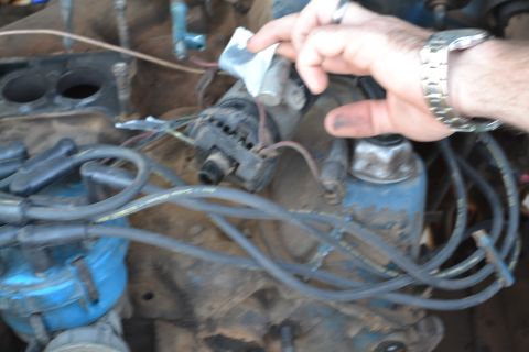 1981 Ford F-250 - A hand works on a vehicle's engine, with spark plug wires and a distributor visible.