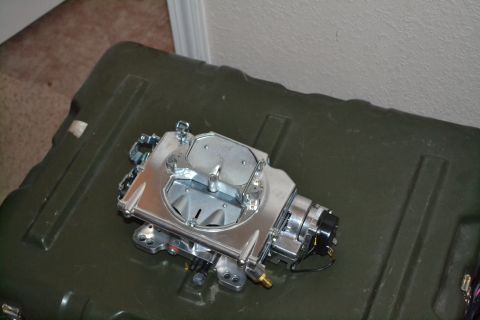 1981 Ford F-250 - A close-up of a carburetor, a crucial engine part, is shown resting on a large green storage container.