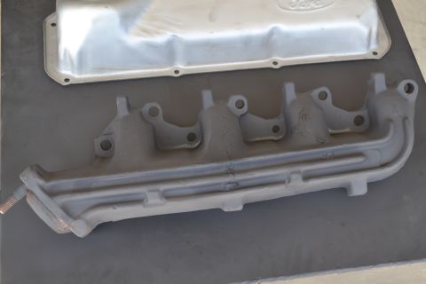 1981 Ford F-250 - A Ford valve cover and exhaust manifold are displayed on a dark surface, with a "SUPERMOTORS.NET" watermark in the corner.