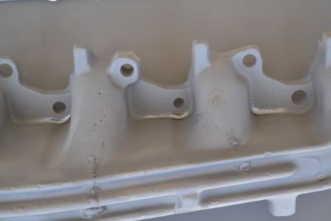 1981 Ford F-250 - Close-up of a gray exhaust manifold, showing its internal structure and mounting points.