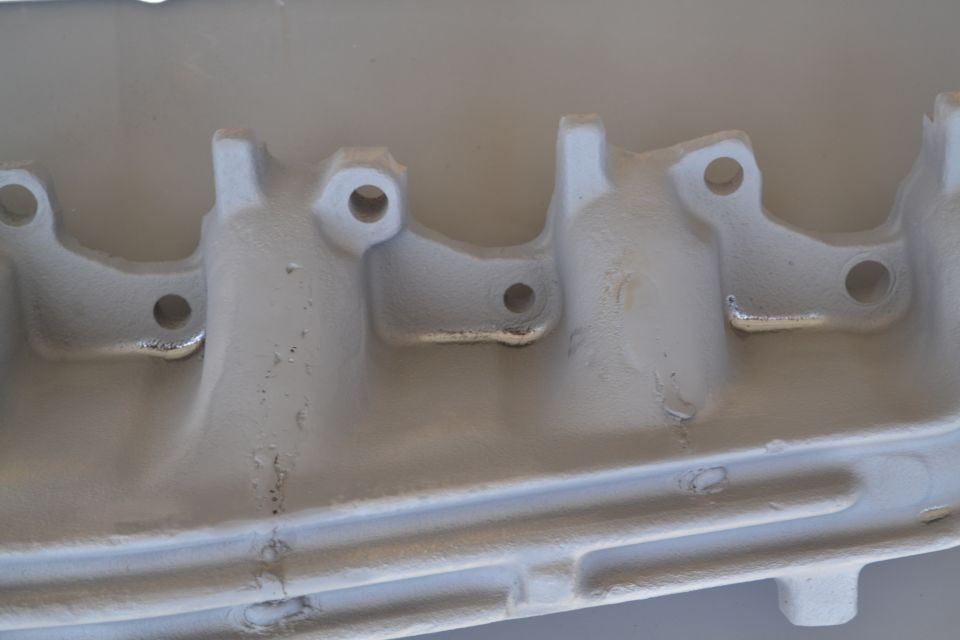 Gray exhaust manifold with visible bolt holes and casting details