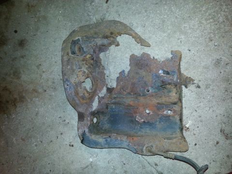 1995 Ford Bronco - A corroded metal bracket, likely a vehicle part, shows significant wear and tear.