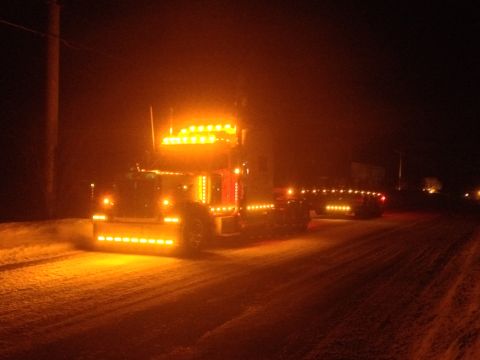 2003 Peterbilt 379 - A truck is illuminated by its many amber lights while driving on a snowy road in the dark.