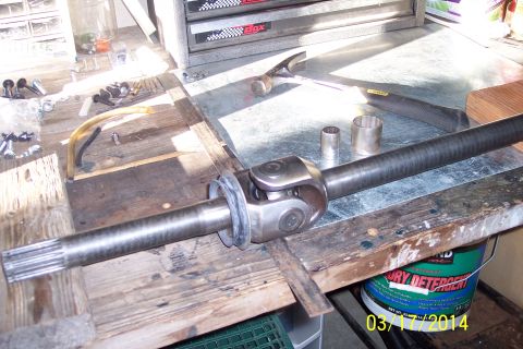 1973 Ford F-250 - A driveshaft and universal joint are laid out on a workbench, ready for repair or installation.