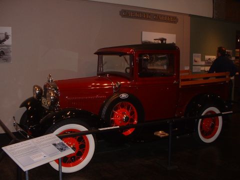 1999 Ford Crown Victoria - A red pickup truck, likely a 1928 Ford Model A, is displayed indoors with a descriptive plaque.