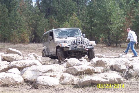 1990 Ford Bronco - A Jeep Wrangler is shown maneuvering through a challenging rocky terrain on an off-road trail.
