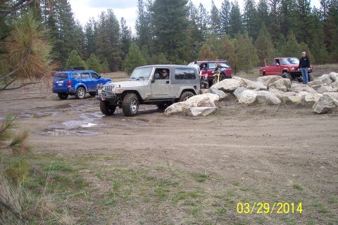 1990 Ford Bronco - Multiple off-road vehicles are seen maneuvering on a dirt and rock-strewn course.