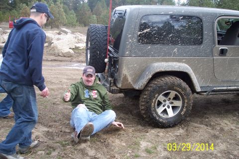 1990 Ford Bronco - A man gives a thumbs-up next to a muddy Jeep Wrangler, with another person standing nearby.