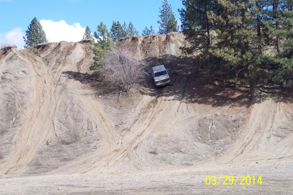 Silver SUV on a steep dirt hill with tire tracks