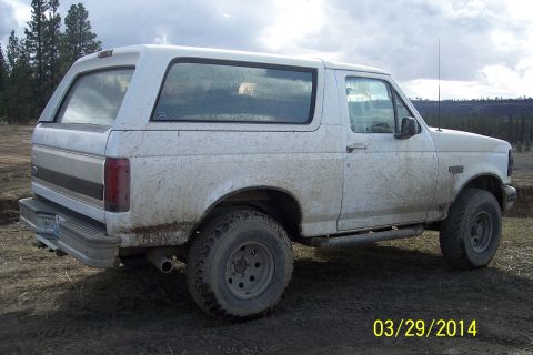 1990 Ford Bronco - Mud-covered 1990 Ford Bronco seen from the side, parked outdoors.