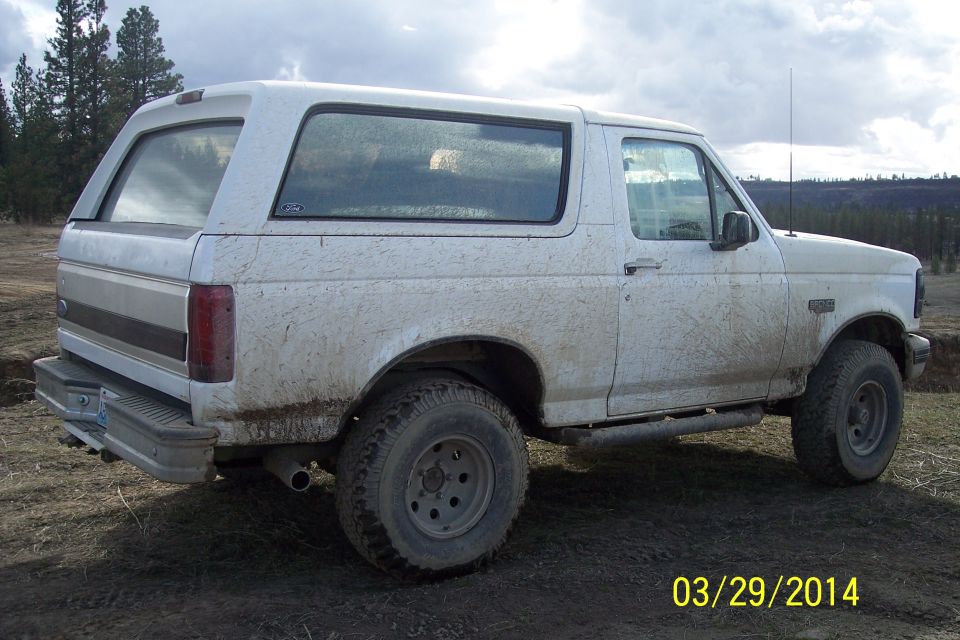 White 1990 Ford Bronco side view, covered in mud